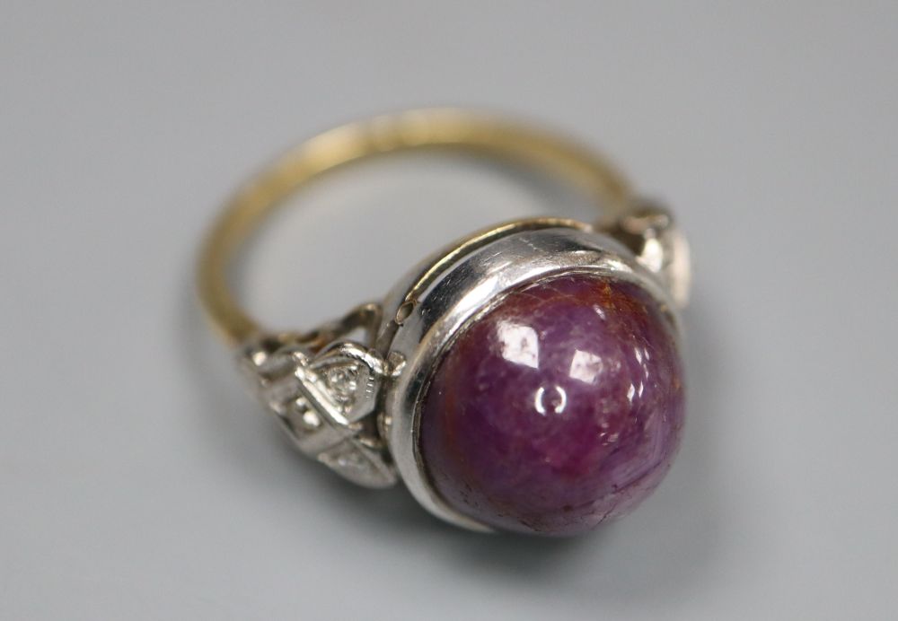 An 18ct and plat, cabochon purple star sapphire set ring, with diamond set shoulders, size N, gross 7.3 grams.